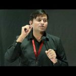 this is the image of krishan Chahal giving speech at TED event. He is wearing black shirt